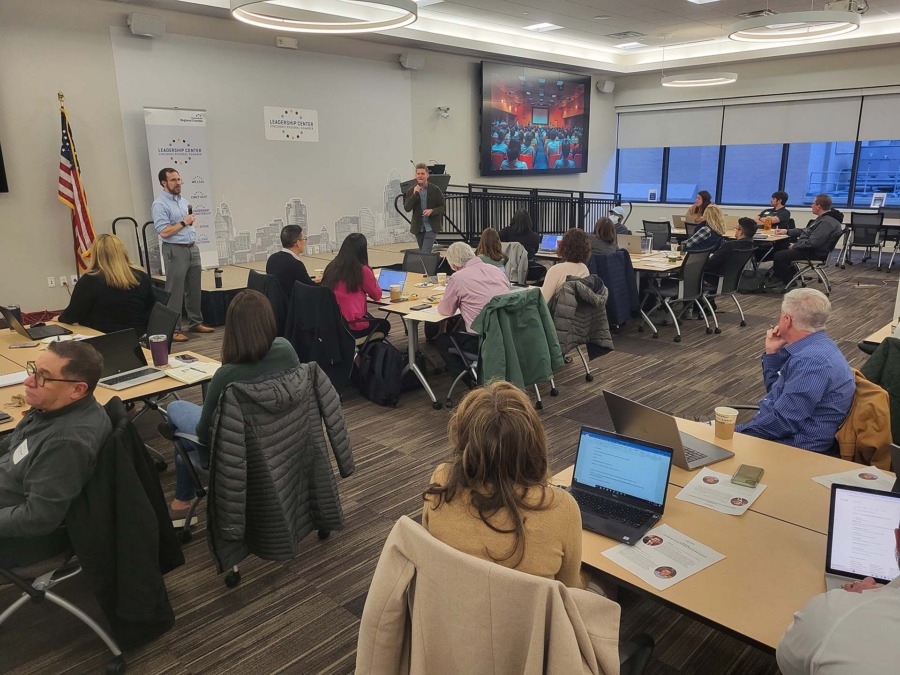 Dennis Cheatham and David Seidl present in front of a conference room of 40 people with laptops