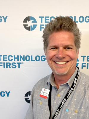 a portrait of dennis cheatham in front of a Technology First photo drop